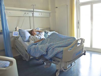 Krankenbett-TV Eine Dame, die einsam in ihrem Krankenbett im Krankenhaus liegt
